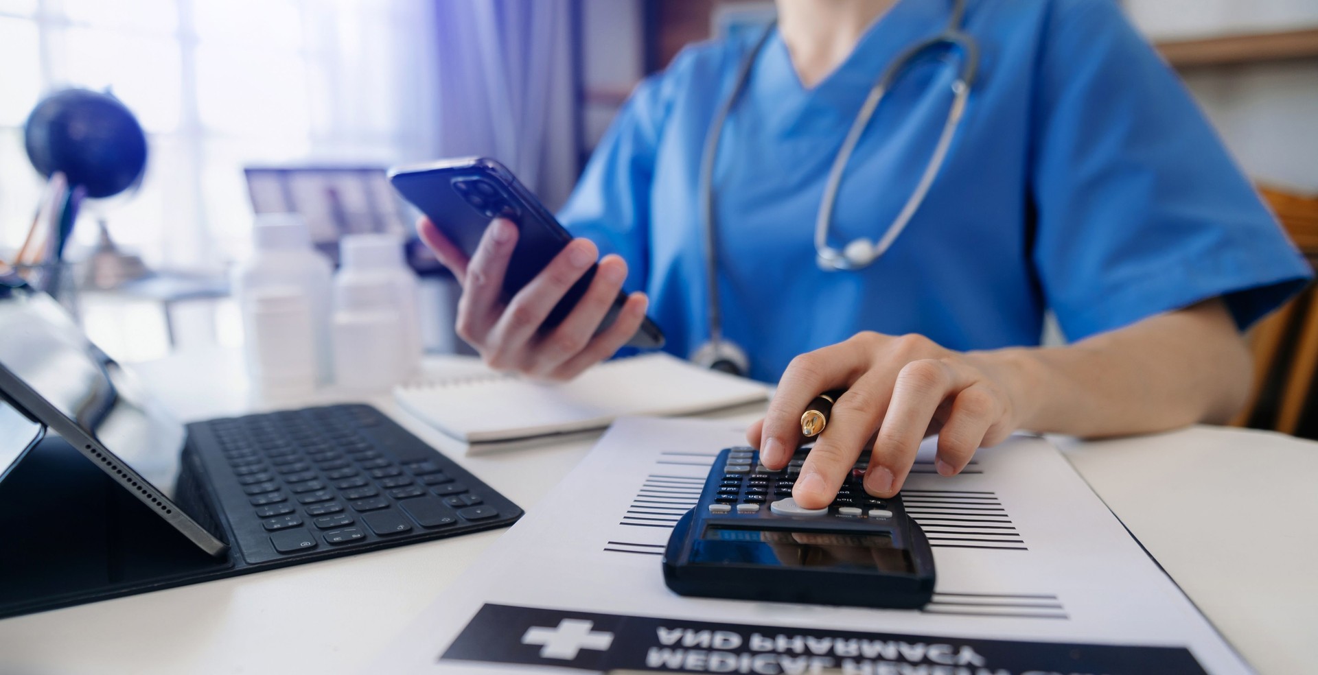 Healthcare costs and fees concept.Hand of smart doctor used a calculator and smartphone, tablet for medical costs at hospital